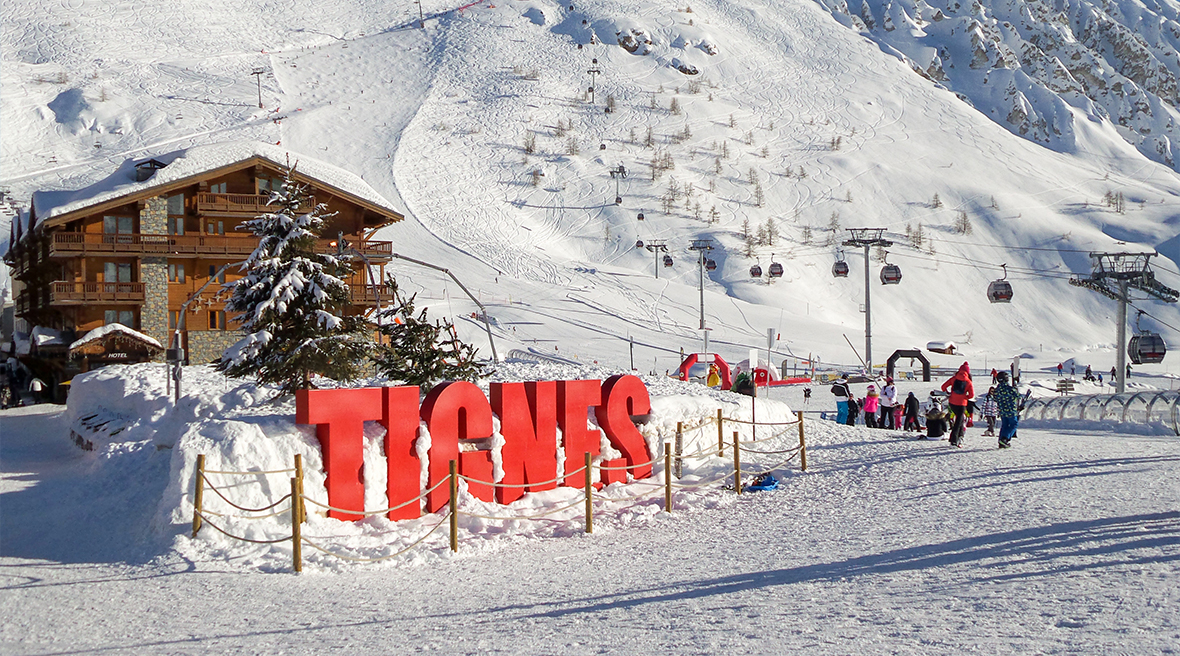 Big red letters spelling out TIGNES set into the snow at the base of a ski slope
